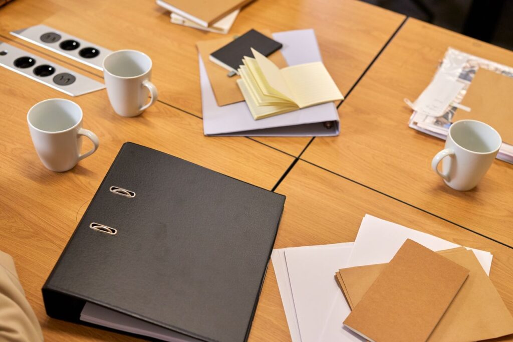 Photograph of a neat office desk with binders, papers, and coffee mugs arranged neatly, offering a professional workspace vibe.